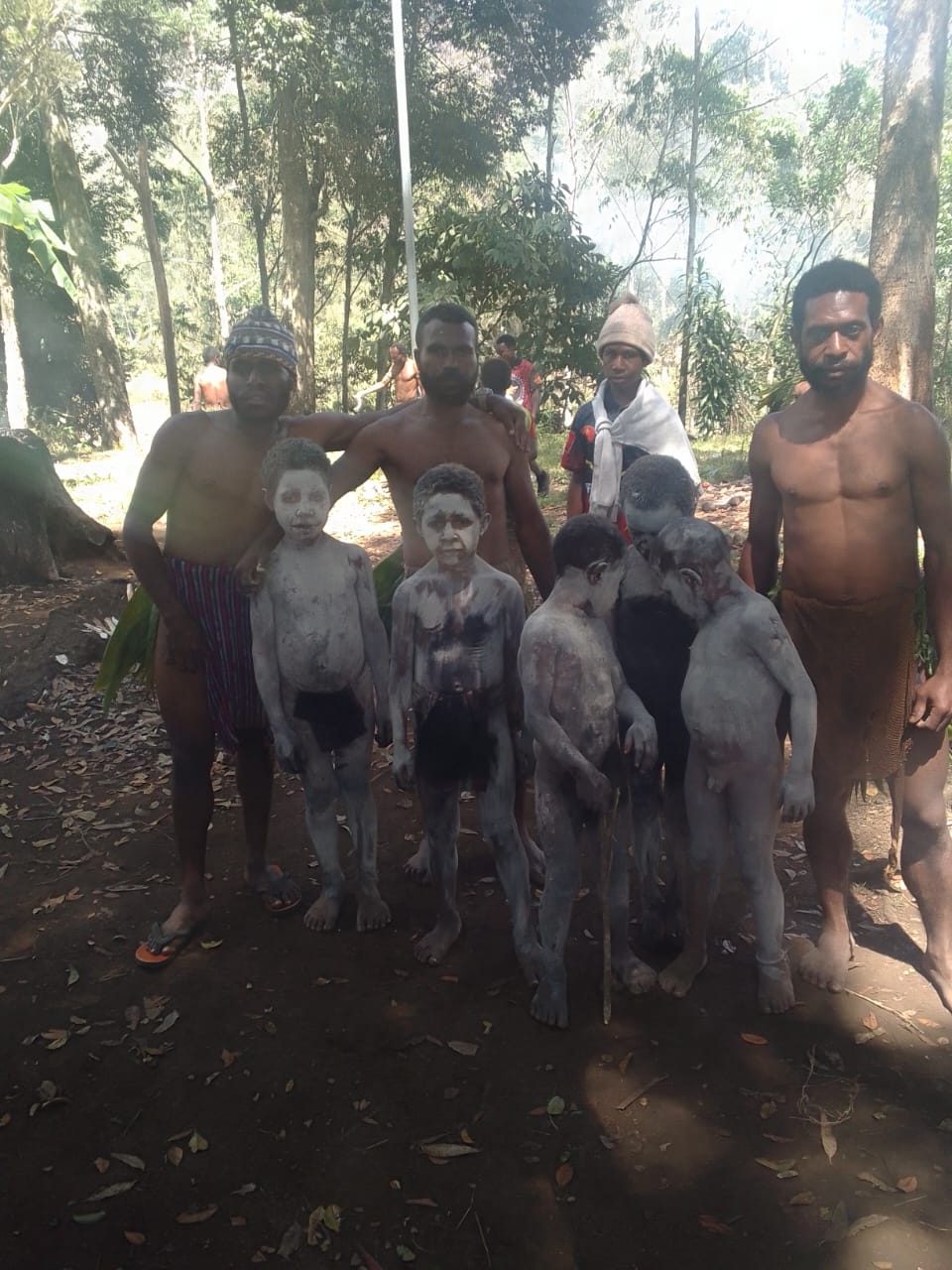 Men with clay-painted faces in traditional dress